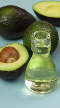 avocats et petite bouteille en verre d'huile, en gros plan, sur un fond bleu