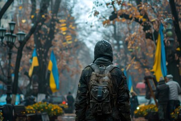 Fototapeta premium Person in Hoodie and Backpack Walking Through a Park with Ukrainian Flags