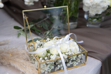 Elegant glass jewelry box filled with white roses for wedding ceremony