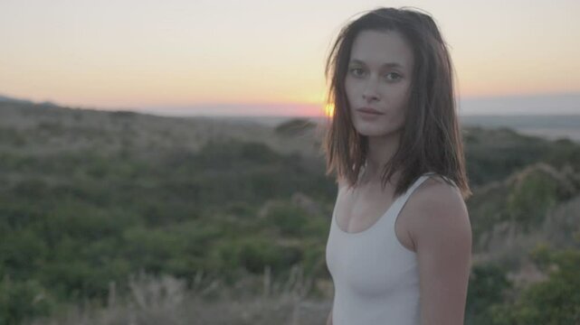Slow motion. Gorgeous young woman with a charming smile against the backdrop of a gentle magnificent summer sunset. Changing focus