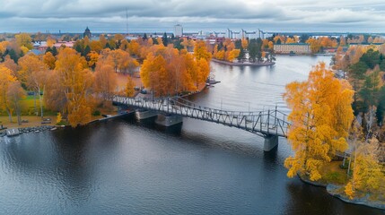 This aerial photograph captures the scenic beauty of an old metal bridge in a park filled with colorful autumn trees, blending natural and urban elements harmoniously.
