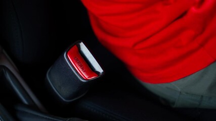 A man takes the car keys from the seat and sits down, after which he fastens his seat belt close-up