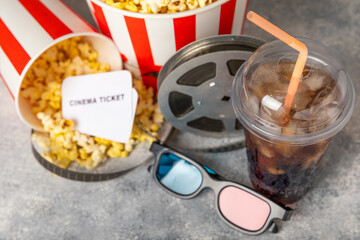 Tasty popcorn in buckets and cold cola drinks with cinema tickets, movie clapper and 3D eyeglasses...