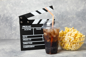 Tasty popcorn in buckets and cold cola drinks with cinema tickets, movie clapper and 3D eyeglasses...