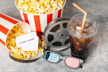 Tasty popcorn in buckets and cold cola drinks with cinema tickets, movie clapper and 3D eyeglasses...