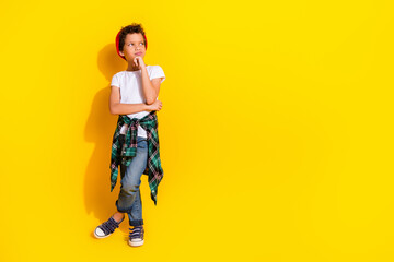 Full size photo of small charming boy look skeptical empty space wear trendy white outfit isolated on yellow color background