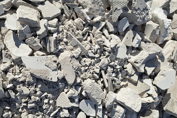 Post-renovation debris: concrete, brick, and gypsum fragments create a dusty texture. Chaotic scene of broken materials and construction waste. The aftermath of extensive building work. Cracked bricks