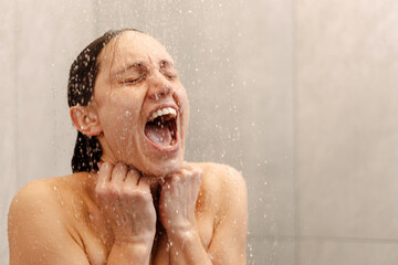 Brunette woman screaming in the shower under cold water jet