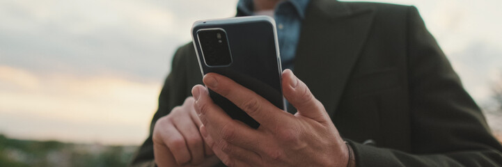 Close-up of a man's hands using a smartphone, panorama