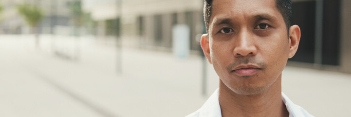 Obraz premium Close up, young businessman looks at the camera while standing in business district
