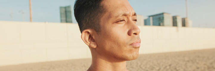 Obraz premium Close up, young athletic man standing on the beach, panorama