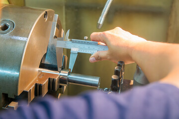 Close up scene the turning machine operator measuring dimension of metal shaft parts by Vernier...