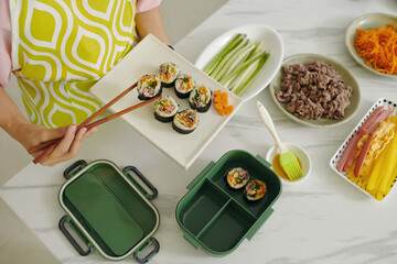 High angle view of housewife packing kimbap in lunchbox