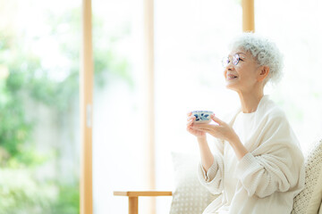 お茶を飲みながら外を眺めるシニア女性