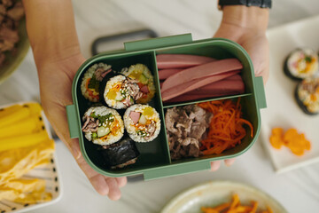 Top view of woman packing korean food in lunchbox