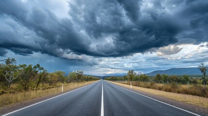 Naklejka premium The straight path of Matilda Highway under thick clouds in Queensland