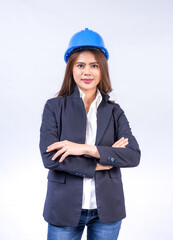 Beautiful female engineer with long hair wearing a blue helmet with her arms crossed on gray background.