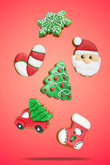 Tasty Christmas cookies of different shapes in air on red background