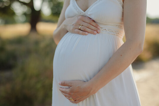 pregnant woman holding her baby belly in a white dress
