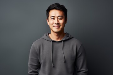 Portrait of a glad asian man in his 30s dressed in a comfy fleece pullover isolated on minimalist or empty room background
