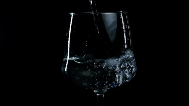 water is poured into a glass on a black background