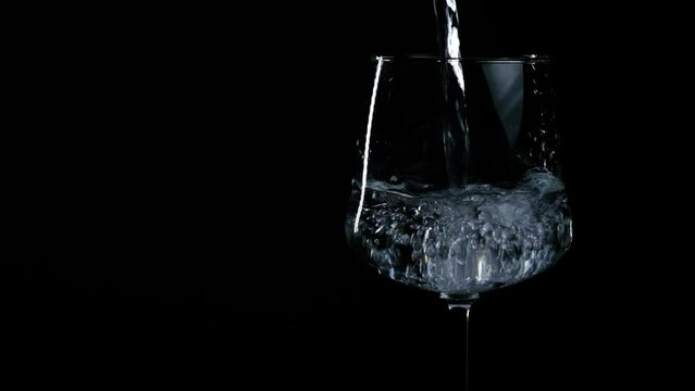 water is poured into a glass on a black background