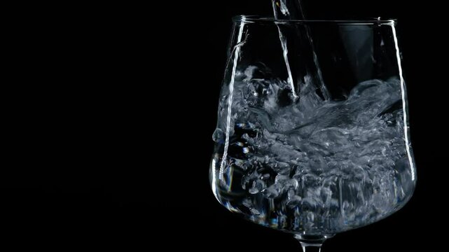 water is poured into a glass on a black background
