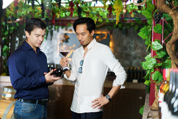 Diverse people testing wine together inside the wine cellar.