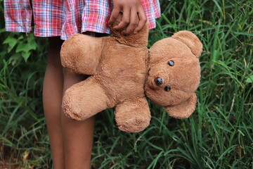 Child holding teddy bear in hand