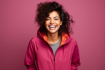 Fototapeta premium Portrait of a happy indian woman in her 30s wearing a functional windbreaker in solid color backdrop
