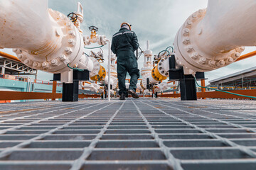 Naklejka premium Male worker inspection at steel long pipes and pipe elbow in station oil factory during refinery valve of visual check record pipeline oil