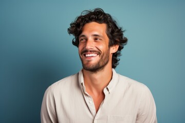 Fototapeta premium Portrait of a happy man in his 30s wearing a simple cotton shirt while standing against solid color backdrop