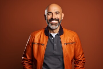 Obraz premium Portrait of a happy man in his 40s sporting a stylish varsity jacket isolated in solid color backdrop