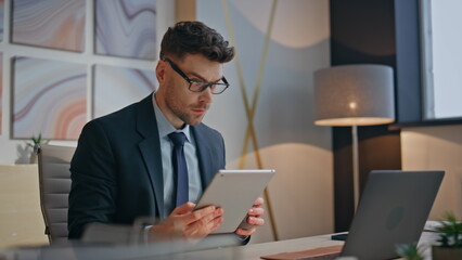 Serious specialist watching tablet comparing computer screen at office closeup