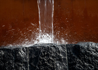 Water pours from a gutter and falls on a stone