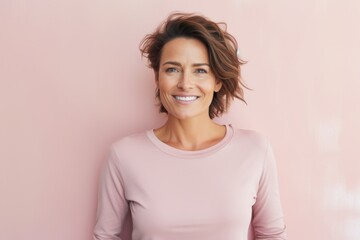 Obraz premium Portrait of a smiling woman in her 40s sporting a long-sleeved thermal undershirt on solid pastel color wall