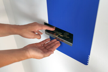 Woman's hands collecting coins from a cash exchange machine