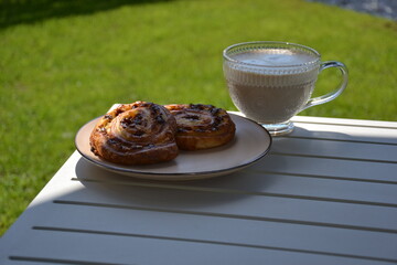 Glass cup of coffee  and  puff pastry outdoor on table in shade
