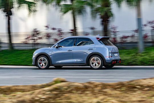 Grey GWM Ora GT in city street, Electric hatchback in movement, green energy vehicle, High Resolution Panning Shot