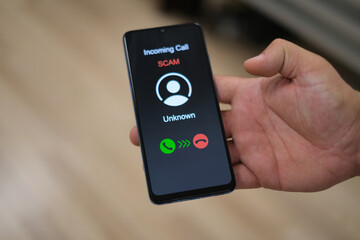 Male hand holding a smartphone with unknown caller displayed on screen. Privacy, fraud, cybercrime and spying concepts