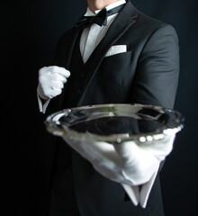 Butler or Waiter in Dark Formal Suit and White Gloves Holding Serving Tray. White Glove Service and Professional Hospitality.