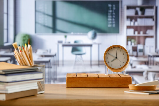 School desk and alarm clock and copy space for product in a big bright classroom interior.