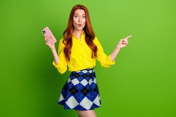 Photo portrait of lovely young lady hold device point amazed empty space dressed stylish yellow...