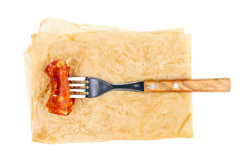 Fork with chorizo sausage on cooking paper isolated on white