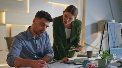 Obraz premium Two colleagues creating project in design studio. Man designer showing paper