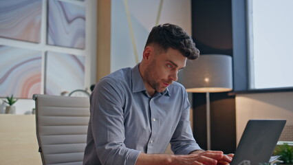 Tensed boss typing laptop keyboard at private cabinet closeup. Man touching head