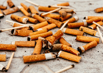 Cigarettes, matches and cigarette butts are scattered on the asphalt and road. Smoking is harmful to human health.