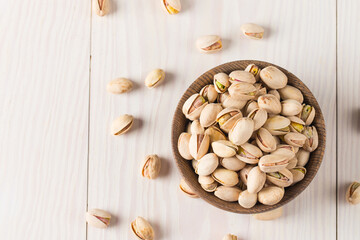 Organic roasted pistachio nuts in a wooden bowl. Top view. 