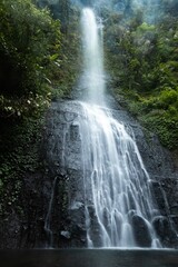 Obraz premium Captivating waterfall in slow shutter, highlighting unique water flow. Lush greenery contrasts beautifully