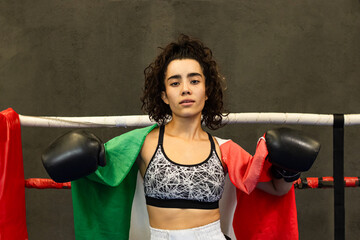 Mexican athlete resting on the ropes of the ring with the flag on her back